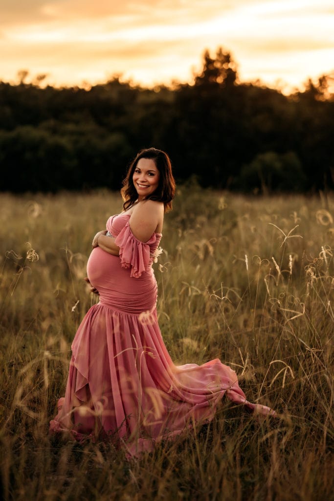 maternity photography in a pink dress in a field
