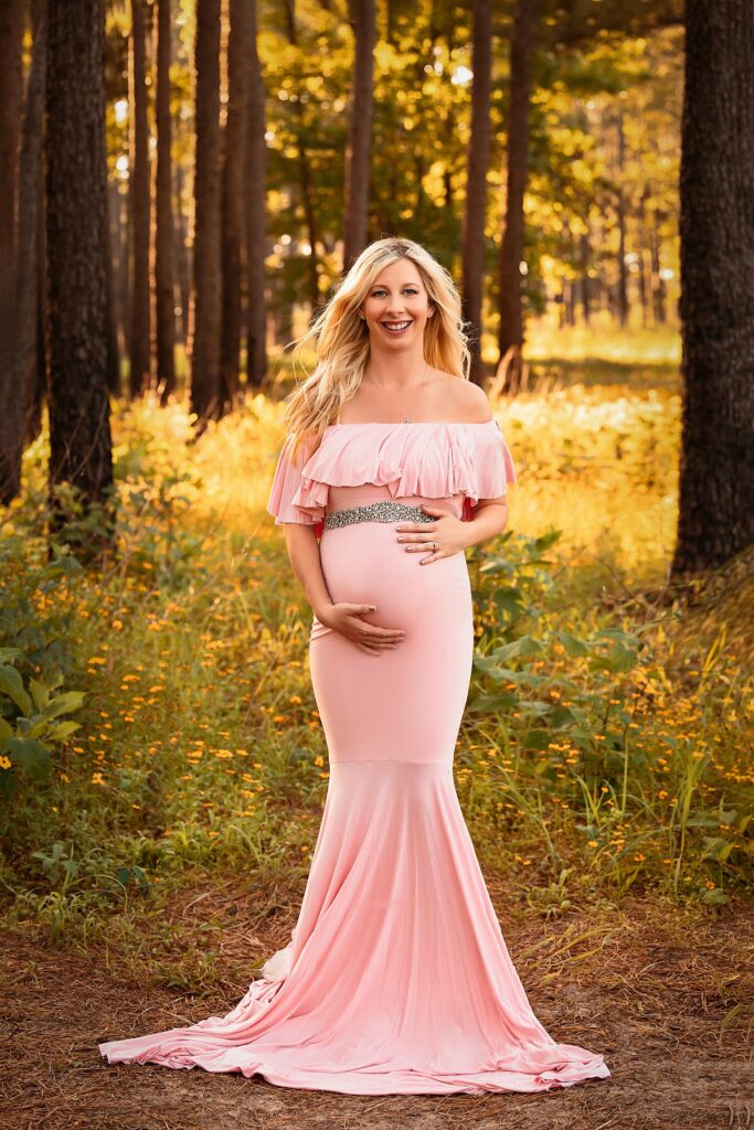 pregnant woman in pink maternity gown with silver belt in a golden forest